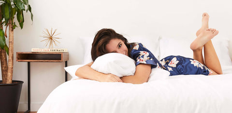 A young woman lying on an all white made with Slumber Cloud products