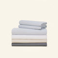 A stack of neatly folded Slumber Cloud Performance Sheet Sets on a cream background