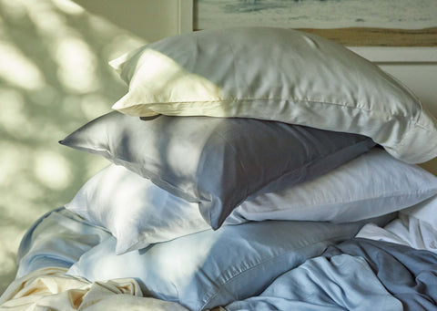 A stack of Slumber Cloud pillows and pillowcases with the evening sun shining on them.