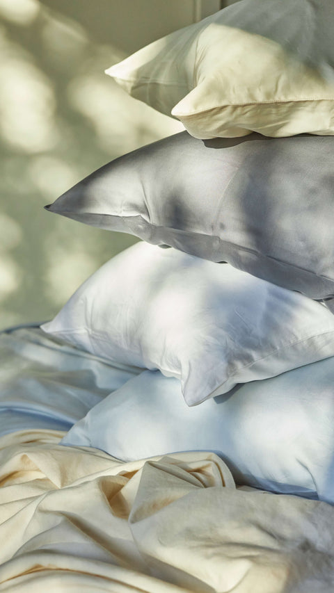 A stack of Slumber Cloud pillows and pillowcases with the evening sun shining on them.