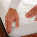 Detailed close up of a man putting the Slumber Cloud Core Mattress Pad on mattress