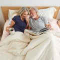 A couple lying in bed with the Slumber Cloud Down Comforter made with temperature regulation technology