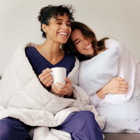 Two woman holding the Slumber Cloud Plush Throw and Performance Pillowcase with Outlast temperature regulation technology